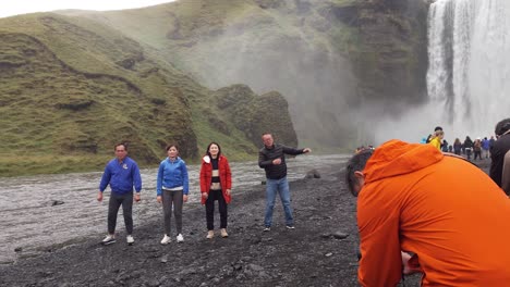 Group-of-Asian-middle-aged-tourists-posing-for-a-funny-picture-at-the-Skogafoss-waterfall-in-Iceland