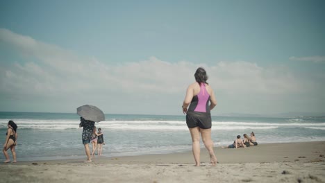 Turistas-De-Playa-Limpia-Caminan-Hacia-Las-Olas-Del-Océano-Con-Otras-Personas-Tomando-El-Sol,-Filipinas