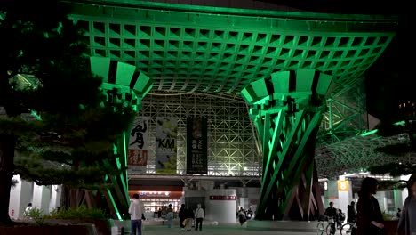 Beleuchtetes-Tsuzumi-Trommeltor-Des-Osteingangs-Des-Bahnhofs-Kanazawa-Bei-Nacht,-Während-Einheimische-Vorbeigehen