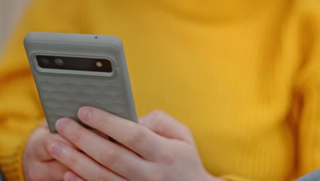 Ausgeschnittene-Ansicht-Einer-Person-Im-Gelben-Sweatshirt,-Die-Ihr-Mobiltelefon-Benutzt