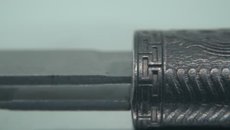 Eine-Makro-Nahaufnahme-Eines-Alten-Silbermessers,-Einer-Chinesischen-Antiken-Waffe,-Einer-Historischen-Vintage-Klinge,-Eines-Alten-Dekorativen-Stahls,-Eines-Traditionellen-Dolches,-Professioneller-Beleuchtung,-Filmischer-4K-Videoschwenk-Nach-Rechts