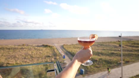 Cocktail-in-a-terrace-held-by-a-woman-with-beautiful-and-amazing-sea-views-landscape-in-a-rooftop-bar