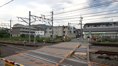 Rote-Warnleuchten-Am-Bahnübergang,-Während-Der-Roller-Neben-Dem-Bahnübergang-In-Arashiyama,-Kyoto,-Anhält