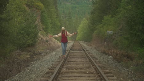 Free-spirit-hipster-woman-balancing-on-abandoned-railway-steel-track