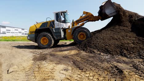 Heavy-wheel-loader-scooping-pile-of-gravel-on-construction-site