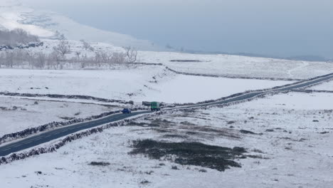 Aerial-Drone-Shot-of-Van-and-Car-Driving-Through-Snowy-Yorkshire-Dales