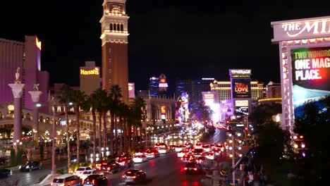 A-vibrant-nighttime-scene-capturing-the-bustling-Las-Vegas-Strip,-with-illuminated-casinos,-crowded-streets,-and-a-stream-of-cars-under-the-neon-glow