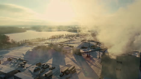 Drone-shot-of-a-pulp-mill-pumping-out-steam-with-snow-covering-the-ground