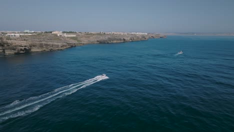 Aerial-shoot-of-boat-moving-fast-in-the-sea-with-a-view-of-the-coastline-in-Peniche-Portugal