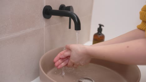 Frau-Dreht-Schwarzen-Wasserhahn-Auf-Und-Wäscht-Hände-Am-Waschbecken-Im-Badezimmer