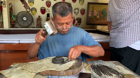 Yogyakarta,-Indonesia---Dec-16,-2023-:-Indonesian-old-man-making-carving-hand-made-wayang-shadow-puppet