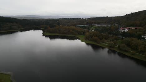 Beautiful-aerial-drone-shot-of-the-landscape-of-the-Cachamuiña-reservoir-on-a-cloudy-day-surrounded-by-trees