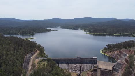 Aerial-view-of-a-dam-and-a-dam-wall-with-mountains-in-the-background