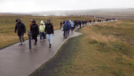 Menschenmenge,-Die-An-Einem-Regnerischen-Tag-Auf-Dem-Nassen-Weg-Läuft,-Um-Den-Gullfoss-Wasserfall-In-Island-Zu-Besuchen