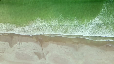 Aquamarine-ocean-waves-gently-crashing-onto-sandy-Paternoster-beach,-top-aerial