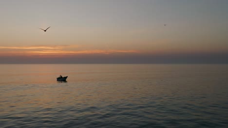 Aerial-shot-of-fishing-boat-in-the-sea-at-sunset-with-seagulls