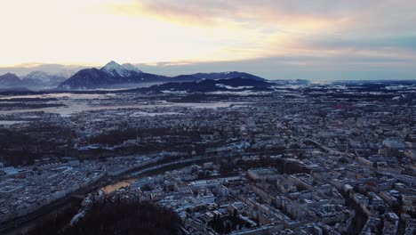 Sensational-aerial-view-of-Salzburg-cityscape-snow-covered-city,-sunset