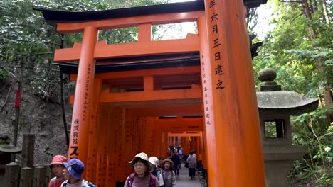 People-are-walking-over-Fushimi-Inari-Taisha,-Kyoto,-vermilion-gates-that-lead-visitors-through-a-mesmerizing-forested-trail-up-the-sacred-Mount-Inari