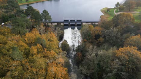 Hydraulic-gates-of-the-Cachamuiña-reservoir-letting-the-water-through-on-a-cloudy-day-surrounded-by-trees-in-winter