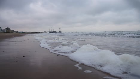 Zeitlupe-Am-Strand-Von-Scheveningen,-Niederlande,-Bei-Bewölktem-Wetter-Und-Kleiner-Schaumwelle