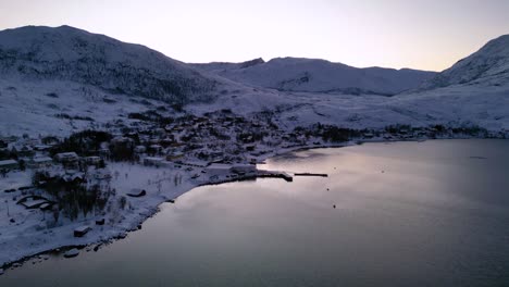 Cinematic-view-of-Norwegian-fjords-and-Ersfjordvegen-village-with-snowy-mountains-and-blue-sea