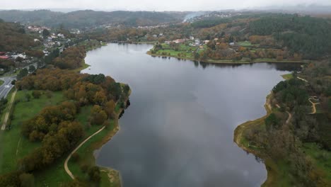 Wonderful-aerial-drone-shot-of-the-landscape-of-the-Cachamuiña-reservoir-on-a-cloudy-day-surrounded-by-its-roads,-avenues-and-trees