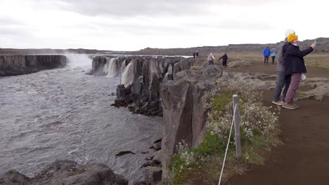 Linda-Pareja-Joven-Tomando-Una-Foto-Selfie-En-La-Cascada-Selfoss-En-Islandia