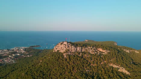 Aerial-4K-drone-footage-of-a-hill-with-the-Turkey-flag-waving-about-the-city-of
Kemer