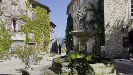 Small-village-square-in-a-historic-stone-town-in-France-in-good-weather-with-a-beautiful-atmosphere-and-plants-on-the-ancient-houses