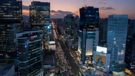 Seoul-Aerial-Hyperlapse-with-Tilt-Zoom-Out-From-Seocho-daero-Road-Night-Car-Traffic-to-Gangnam-Office-Corporate-Buildings-Against-Picturesque-Sunset-Sky---Aerial