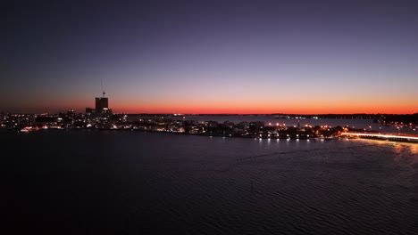 Drone-flying-over-Swan-river-in-Perth-at-sunset-as-the-sky-lights-up-orange