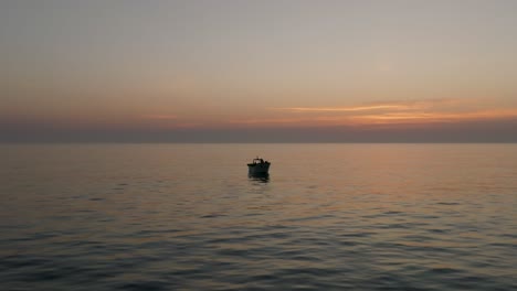 drone-shot-of-a-fishing-boat-in-the-calm-sea-at-sunset