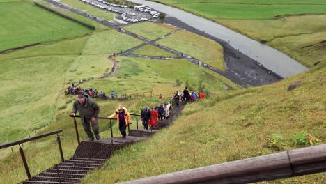 Tourists-climbing-the-stairs-to-the-top-of-Skógafoss-waterfall-in-Iceland---Top-down-view