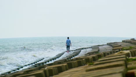 Young-lonely-man-walking-towards-the-dangers-of-incoming-ocean-tide