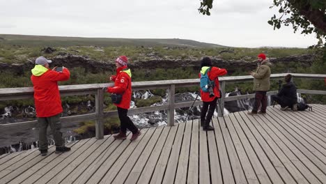Gruppe-Von-Touristen,-Die-Den-Wasserfall-Hraunfossar-In-Island-Genießen