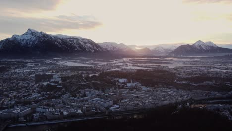 Salzburg-winter-snow-covered-cityscape-at-sunset,-aerial-establishing-view
