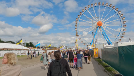People-Walking-at-Oktoberfest-Fairgrounds,-Ferris-Wheel-in-Background