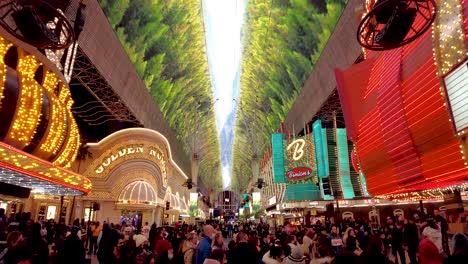 Captivating-drone-footage-showcasing-the-electric-atmosphere-of-Fremont-Street,-Las-Vegas,-with-its-dazzling-neon-canopy-and-the-hustle-of-delighted-crowds