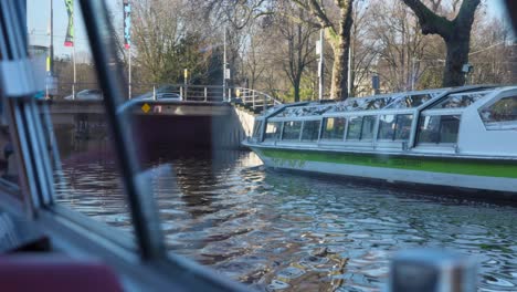 View-from-the-window-of-canal-tour-boat-in-Amsterdam-passing-another-tourist-boat