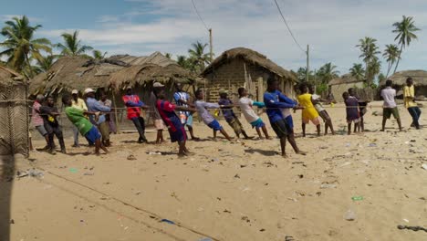 Eine-Gruppe-Von-Männern-Zieht-Am-Strand-Eines-Dorfes-In-Ghana-Ein-Fischernetz-An-Einem-Seil-Hoch
