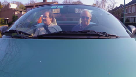 Father-and-son-driving-in-cabriolet-through-village-car-mount-action-cam