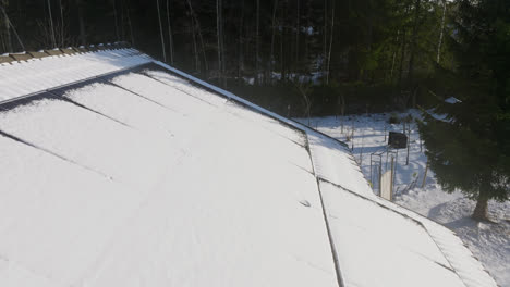 Drohne-Fliegt-Rückwärts-über-Matschige-Solarpaneele-Auf-Einem-Hausdach,-Winterabend