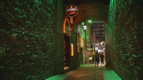 Gente-Caminando-En-El-Callejón-Del-Arco-De-Los-Comerciantes-Por-La-Noche-En-Dublín,-Irlanda