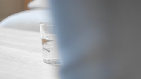 A-Hand-Placing-a-Glass-of-Water-Onto-the-Table---Close-Up