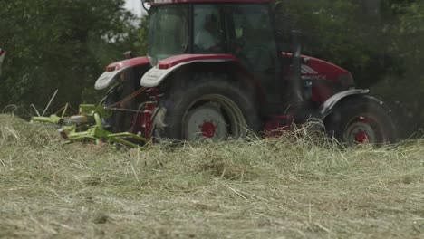 Landwirt-Bedient-Traktor-Mit-Kreiselrechen-über-Feldern