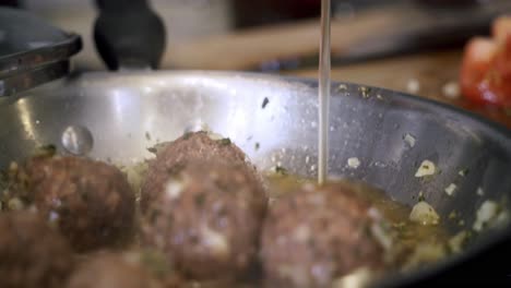 close-up-of-pouring-vegetable-broth-into-pan-of-meatballs-Preparing-ingredients-to-make-vegan-beyond-meatballs-with-spaghetti-and-meat-sauce