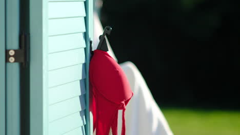 Red-swimsuit-hanging-on-a-hook-beside-a-beach-house