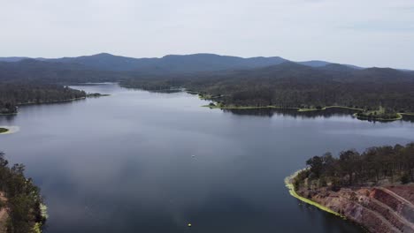 Drohne,-Die-über-Einem-Wunderschönen-See-Mit-Bergen-Im-Hintergrund-Rückwärts-Fährt