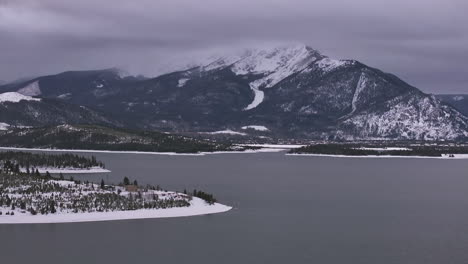 Lake-Dillon-Marina-Keystone-Summit-cove-Colorado-aerial-cinematic-drone-cloudy-snowy-winter-morning-view-downtown-Frisco-Breckenridge-Silverthorne-Ten-Mile-Range-calm-unfrozen-ice-forward-reveal