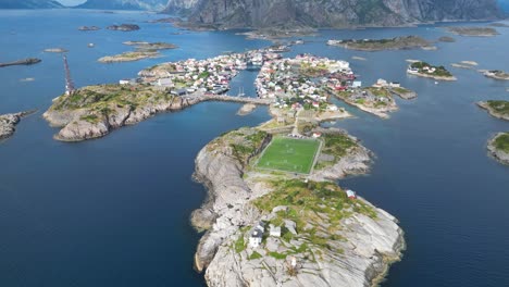 Henningsvaer-Soccer-Field-and-Village-in-Lofoten-Island-Archipelago,-Norway---4k-Aerial-Tilting-Up-Backwards